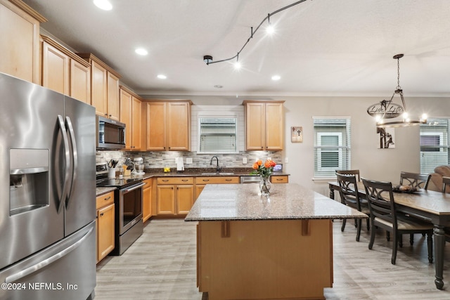 kitchen featuring stainless steel appliances, light stone counters, pendant lighting, light hardwood / wood-style floors, and a kitchen island