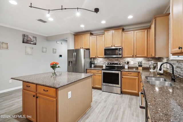 kitchen with dark stone counters, sink, light wood-type flooring, a kitchen island, and stainless steel appliances