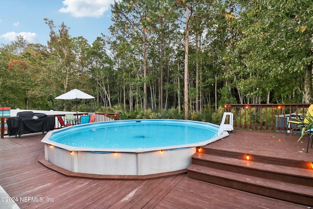 view of swimming pool featuring a grill and a wooden deck