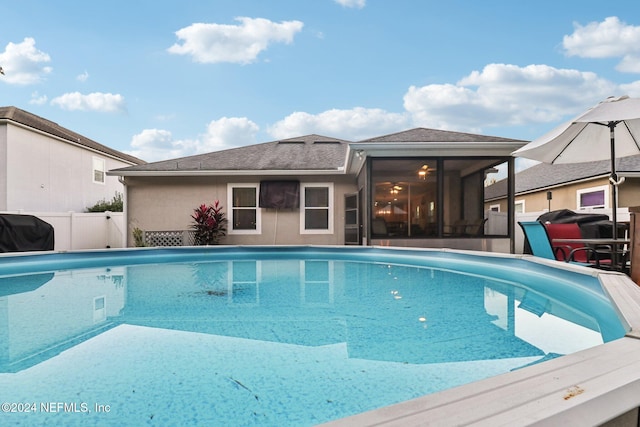 view of swimming pool with area for grilling and a sunroom