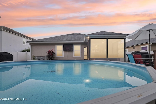 pool at dusk featuring area for grilling