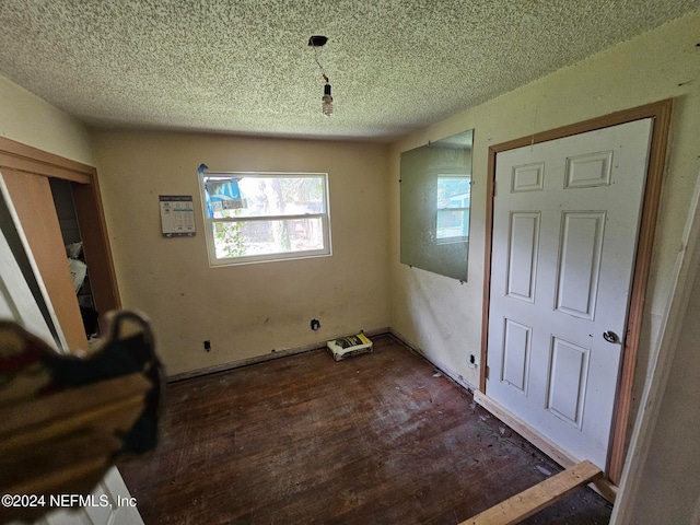 unfurnished dining area with a textured ceiling and dark hardwood / wood-style flooring