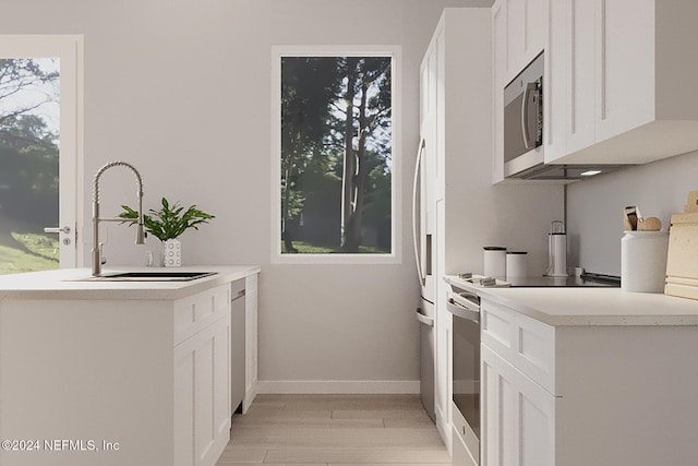 kitchen with white cabinets, a healthy amount of sunlight, white stove, and light hardwood / wood-style floors