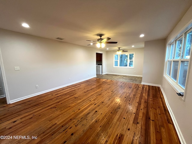 unfurnished living room with ceiling fan, washer / dryer, and dark wood-type flooring