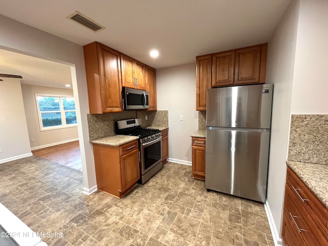 kitchen featuring backsplash, ceiling fan, light stone counters, and stainless steel appliances