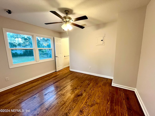 unfurnished room featuring electric panel, ceiling fan, and dark wood-type flooring