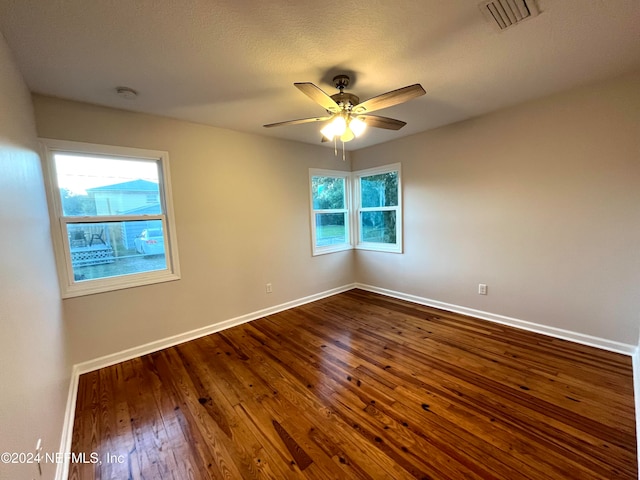 empty room with a wealth of natural light, dark hardwood / wood-style flooring, and ceiling fan