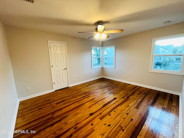 spare room featuring a textured ceiling, hardwood / wood-style flooring, a wealth of natural light, and ceiling fan