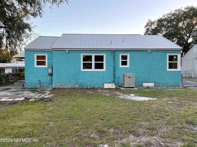 back of property featuring central AC unit and a yard