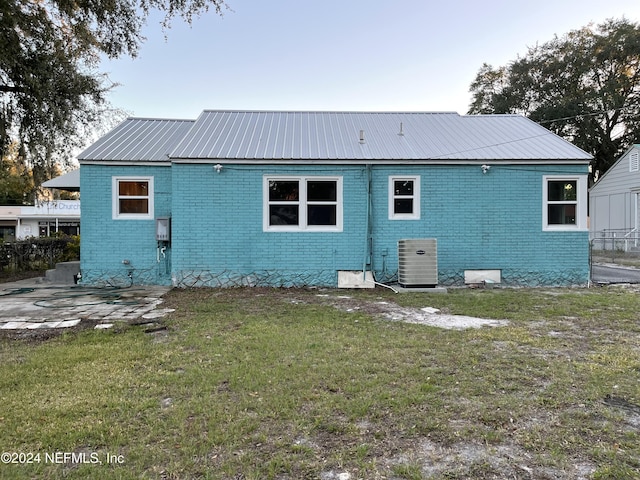 2414 Crill Ave, Palatka, FL 32177 - rear view of house featuring central air condition unit, brick siding, a lawn, and metal roof
