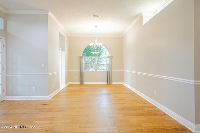 unfurnished dining area with crown molding, an inviting chandelier, and light wood-type flooring