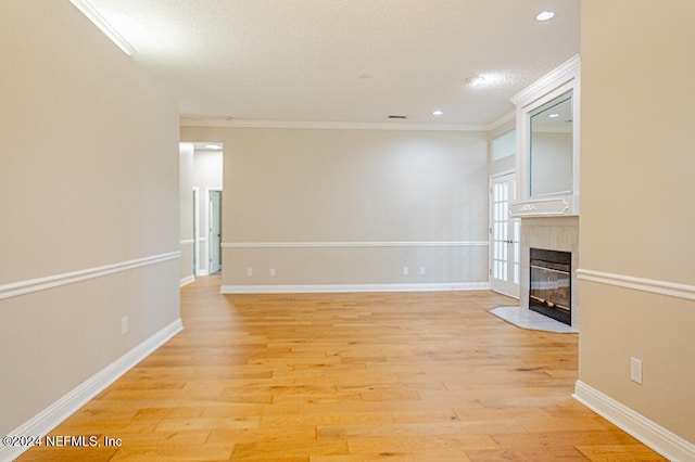 unfurnished living room with light hardwood / wood-style floors, ornamental molding, and a tiled fireplace