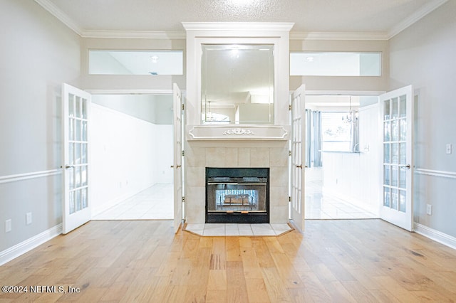 unfurnished living room with a fireplace, french doors, ornamental molding, and light hardwood / wood-style flooring