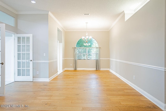 unfurnished dining area featuring a textured ceiling, light wood-type flooring, an inviting chandelier, and ornamental molding