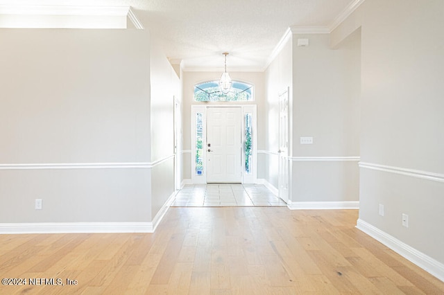 entrance foyer featuring a textured ceiling, light wood-type flooring, and ornamental molding