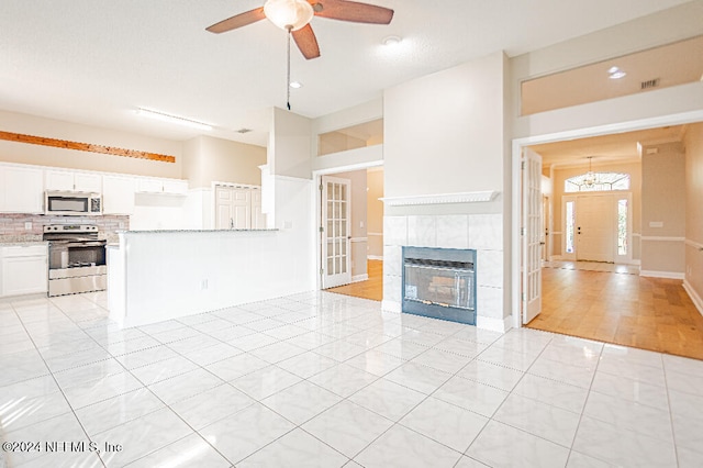 unfurnished living room featuring light hardwood / wood-style floors, ceiling fan, and a tiled fireplace