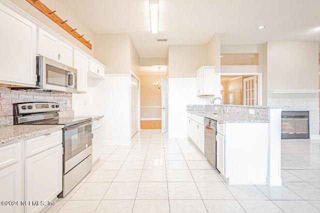 kitchen with appliances with stainless steel finishes, light stone counters, white cabinetry, and sink