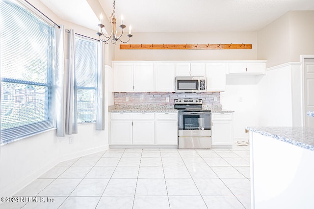 kitchen featuring pendant lighting, white cabinetry, stainless steel appliances, and a wealth of natural light