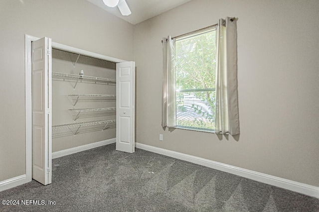 unfurnished bedroom featuring dark colored carpet, ceiling fan, and a closet