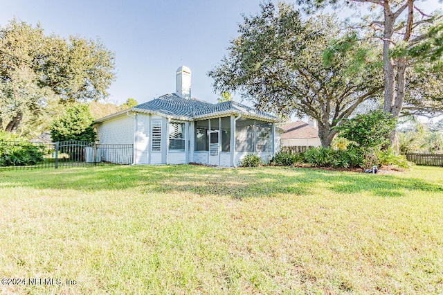 rear view of house featuring a sunroom and a yard