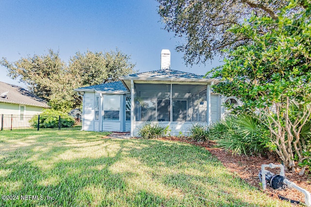 back of house featuring a sunroom and a lawn