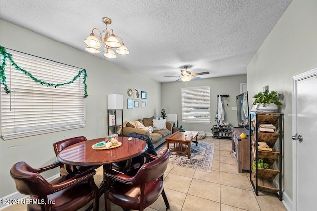 dining room featuring ceiling fan with notable chandelier, light tile patterned floors, and a textured ceiling