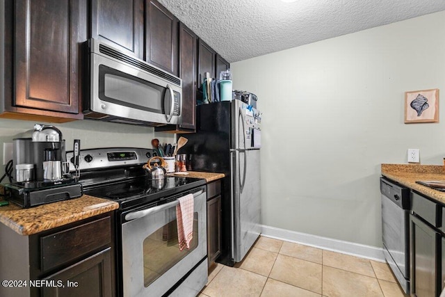 kitchen featuring light stone countertops, light tile patterned floors, a textured ceiling, appliances with stainless steel finishes, and dark brown cabinetry