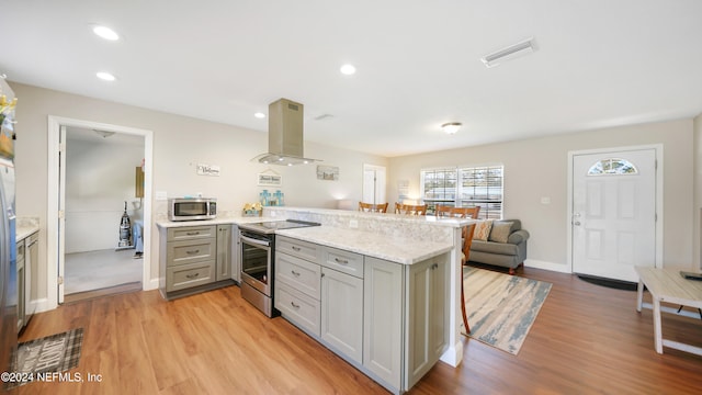 kitchen with kitchen peninsula, appliances with stainless steel finishes, light wood-type flooring, and island range hood