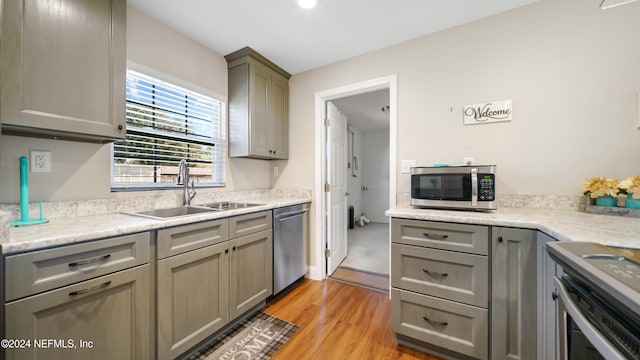 kitchen featuring appliances with stainless steel finishes, light hardwood / wood-style floors, gray cabinets, and sink