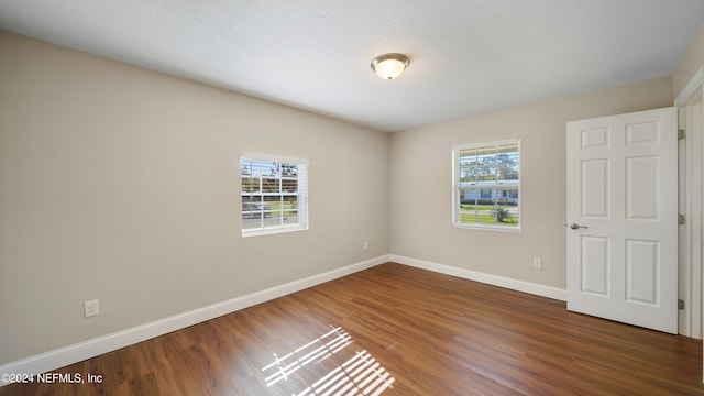 empty room with a textured ceiling and dark hardwood / wood-style flooring