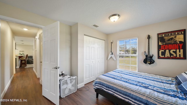 bedroom featuring dark hardwood / wood-style floors, a textured ceiling, and a closet