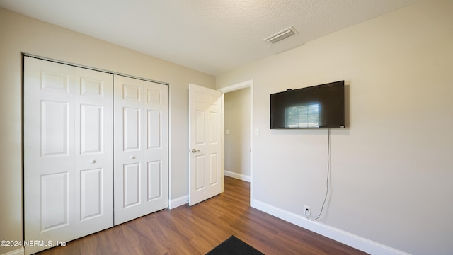 unfurnished bedroom featuring a closet, hardwood / wood-style floors, and a textured ceiling