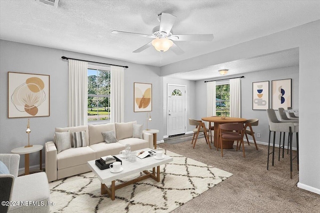 living room featuring ceiling fan, carpet, a healthy amount of sunlight, and a textured ceiling