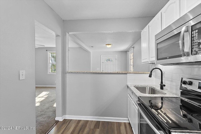 kitchen with sink, dark hardwood / wood-style floors, light stone countertops, white cabinetry, and stainless steel appliances