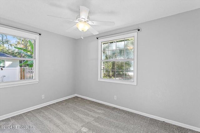 carpeted empty room featuring ceiling fan and a wealth of natural light