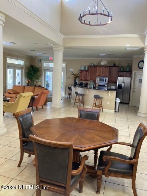 dining space with ornate columns, french doors, sink, crown molding, and light tile patterned floors