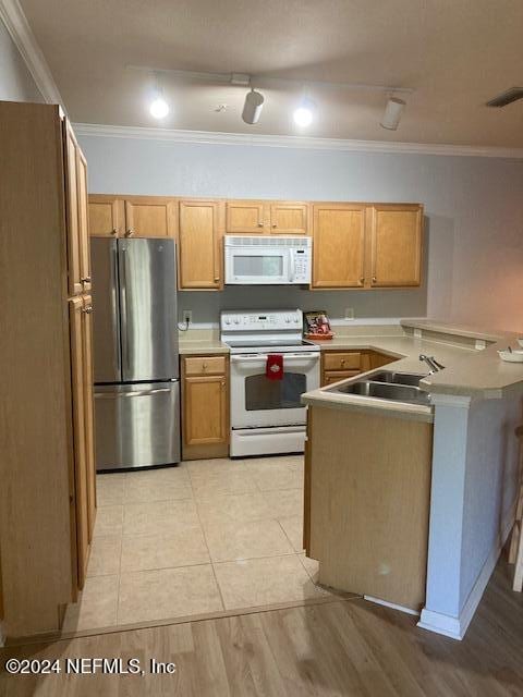 kitchen featuring kitchen peninsula, white appliances, ornamental molding, and sink