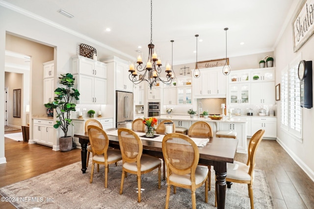 dining space featuring dark hardwood / wood-style floors, ornamental molding, sink, and a chandelier