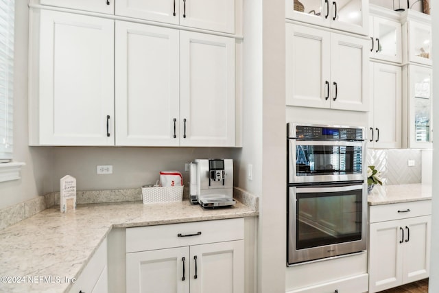 kitchen featuring white cabinetry, double oven, and light stone counters