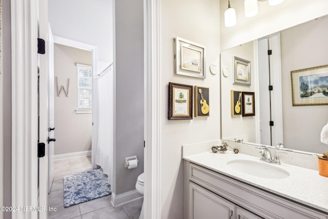 bathroom with toilet, vanity, and tile patterned floors