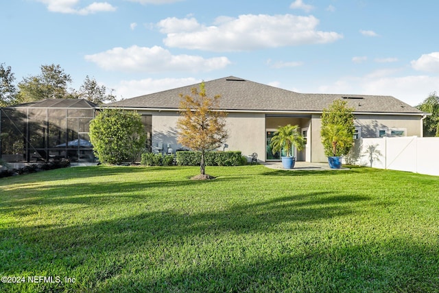 back of property featuring a lawn and glass enclosure