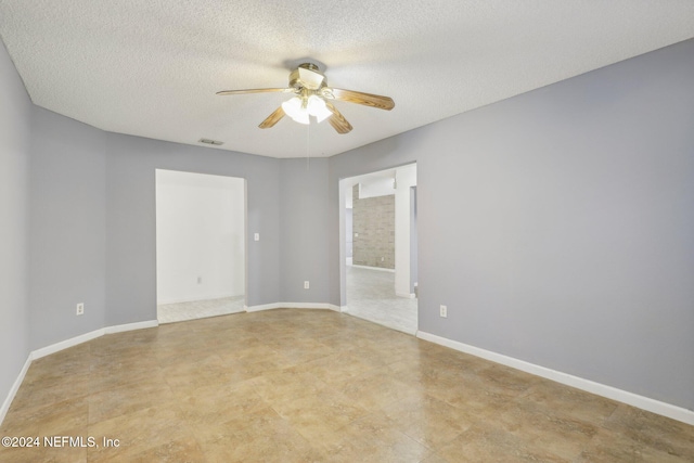 empty room with ceiling fan and a textured ceiling