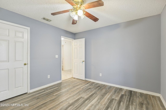 unfurnished bedroom with ceiling fan, wood-type flooring, and a textured ceiling