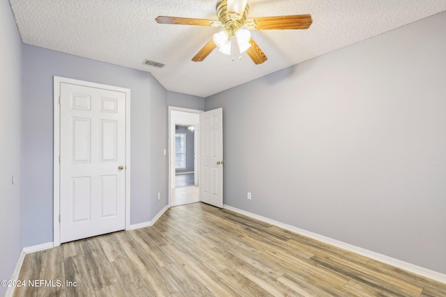 unfurnished bedroom with ceiling fan, a textured ceiling, and light wood-type flooring