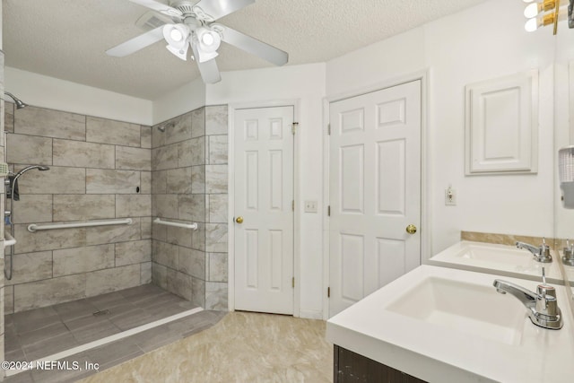 bathroom featuring vanity, a tile shower, a textured ceiling, and ceiling fan