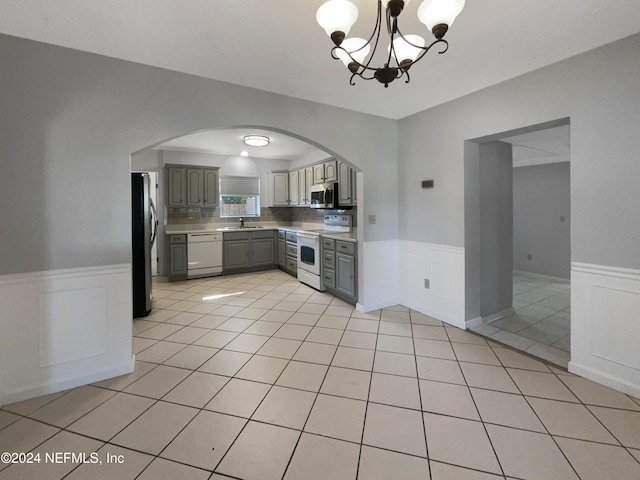 kitchen featuring gray cabinetry, sink, decorative backsplash, appliances with stainless steel finishes, and a notable chandelier