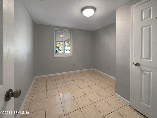 tiled spare room with a textured ceiling