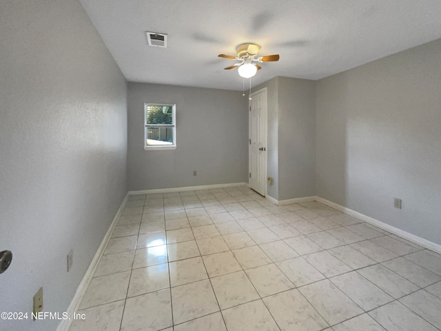 tiled empty room featuring ceiling fan