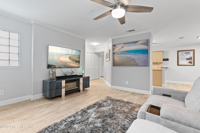 living room with crown molding, ceiling fan, and light wood-type flooring