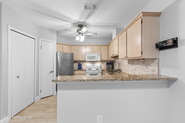 kitchen featuring sink, light stone counters, light hardwood / wood-style flooring, kitchen peninsula, and white appliances